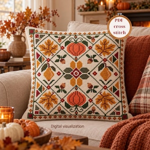 May include: A square throw pillow featuring a cross-stitch pattern with a diamond grid design. The motif includes orange pumpkins, yellow maple leaves, pears, and brown acorns in a seasonal colour palette. Text reads PDF cross stitch.