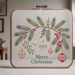 May include: Cross-stitch embroidery in a square wooden hoop. The design features a festive Christmas theme with green pine branches, red berries, and hanging ornaments in white, pink, and silver. The words "Merry Christmas" are stitched in green.