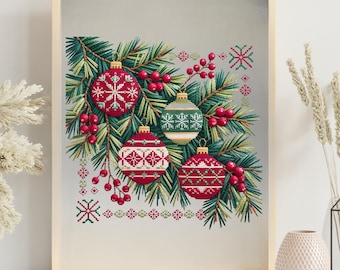 May include: A framed cross-stitch artwork featuring four Christmas ornaments in red, white, and green. The ornaments are decorated with snowflake and geometric patterns, set against a backdrop of evergreen branches and red berries. The artwork is in a light wooden frame.