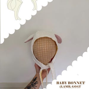 May include: A baby bonnet with a lamb, goat, and bunny design. The bonnet is white with pink ears and a plaid interior. The image includes text that reads "FREE WITH LIBBY LAMB PATTERN PURCHASE (CODE: EASTER)" and "BABY BONNET (LAMB, GOAT AND BUNNY) PDF sewing pattern".