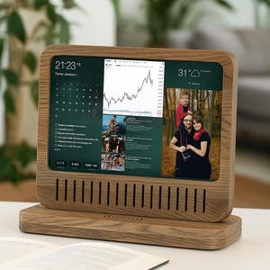 Puede incluir: Un marco de fotos digital de madera que muestra un calendario, un gráfico de bolsa y fotos familiares. El marco tiene una pantalla rectangular con un acabado de veta de madera clara y una base a juego. La pantalla muestra la hora y la temperatura.
