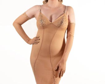 May include: A nude-colored, sleeveless dress with a plunging neckline and a fitted silhouette. The dress is embellished with rhinestones and features sheer long gloves.