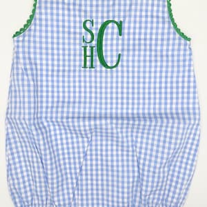 May include: A blue and white gingham baby onesie with green trim and a green embroidered monogram "SHC".