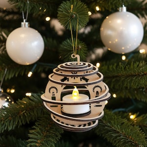 Può includere: Un ornamento natalizio in legno a forma di lanterna, con una piccola candela a LED all'interno. L'ornamento è realizzato in legno a strati con intagli decorativi ed è appeso a un albero di Natale.