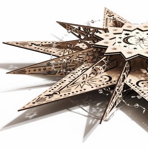 May include: A wooden star-shaped decoration with intricate cut-out designs of stars, moons, and celestial patterns. The natural wood color is accented by a string of clear, round lights. The star has multiple points and layers.