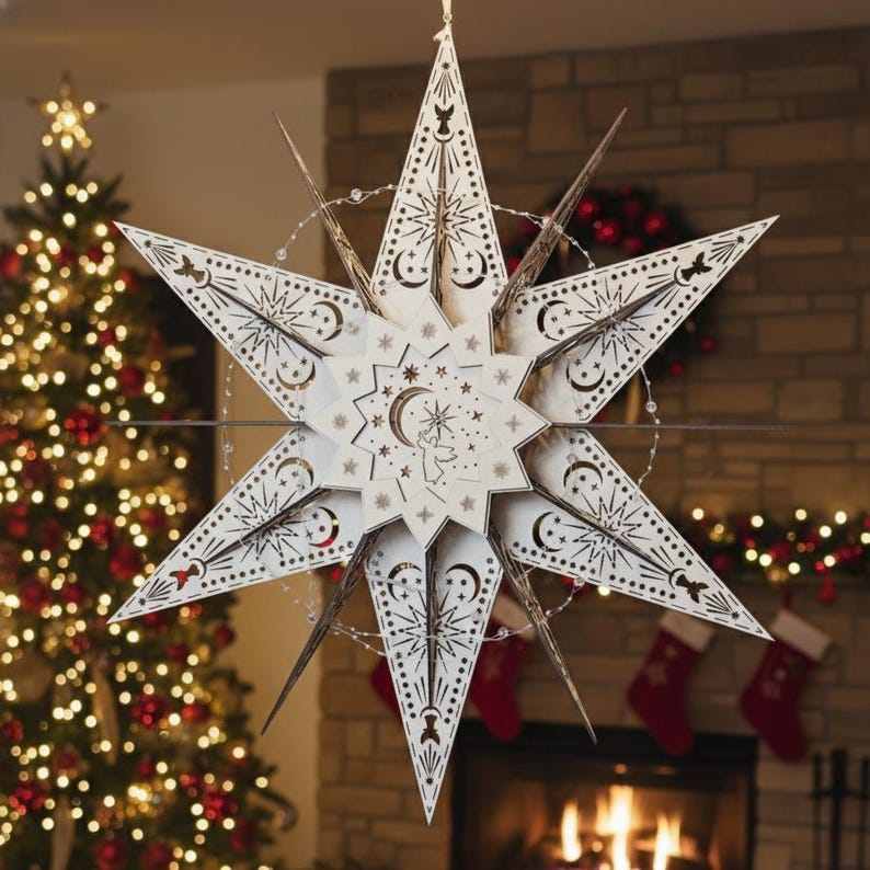 May include: A large, cream-colored star-shaped Christmas ornament with intricate cut-out designs. The star features celestial motifs, including moons and stars, and is suspended in front of a Christmas tree and fireplace. The ornament is illuminated with small lights.