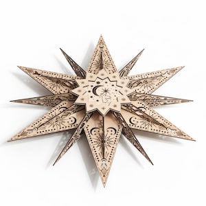 May include: A wooden star-shaped wall hanging with intricate celestial designs. The star features multiple points, each adorned with etched patterns of moons, stars, and suns. The natural wood color contrasts with the dark etched details, creating a striking visual effect.
