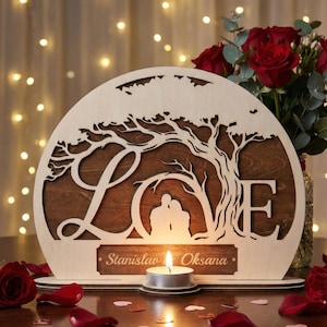 Könnte beinhalten: Hölzernes LOVE-Schild mit Baumdesign, einer Paarsilhouette und einer Kerze. Das Schild besteht aus hellem Holz mit einem dunkelbraunen Hintergrund. Die Namen "Stanislaw Oksana" sind auf dem Schild eingraviert.