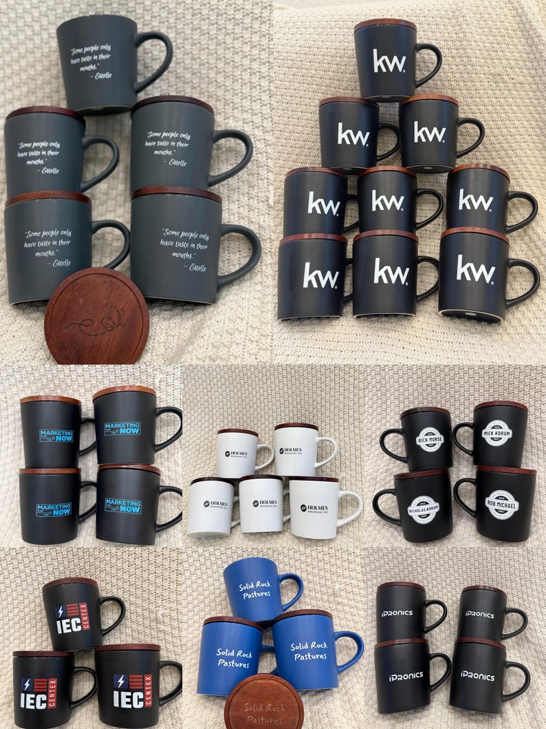 May include: A collection of ceramic mugs with wooden lids. The mugs are in various colors, including dark gray, black, white, and blue. Some mugs have text such as "kw", "Marketing Now", "IEC", and "Solid Rock Pastures".