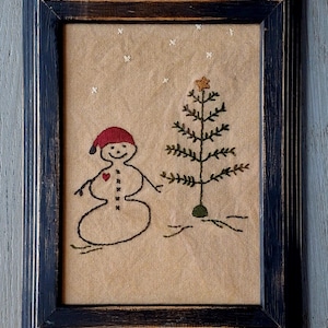 This is a framed 5" × 7" Merry Christmas embroidery with a cute snowman on aged muslin.