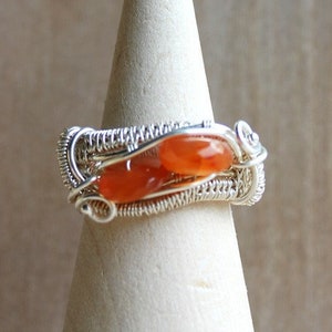 May include: A silver wire wrapped ring with two orange carnelian stones.