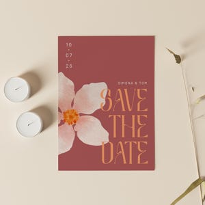 May include: A save the date card with a pink flower and the text "Simona & Tom Save The Date" in orange on a red background.
