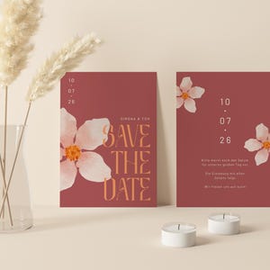 May include: Two red save the date cards with white floral designs and the text "Save the Date" in orange. The date is 10.07.26.