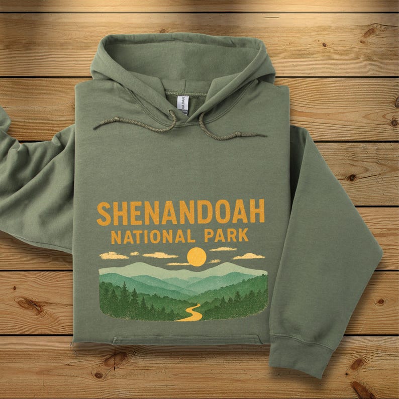 A folded sage green hoodie featuring a yellow and green Shenandoah National Park mountain graphic centered on the chest.
