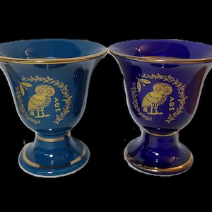 Könnte beinhalten: Zwei Keramikkelche mit goldenen Verzierungen und einem Eulenmotiv. Ein Kelch ist blau und der andere ist türkis.