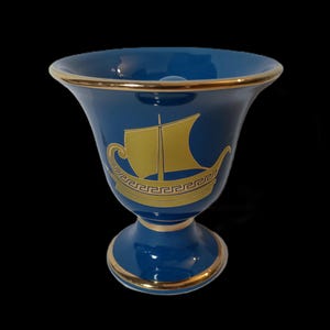 May include: A blue ceramic goblet with a gold rim and a gold design of a ship with a Greek key pattern.