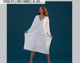 May include: A woman models a white, oversized V-neck dress. The dress is knee-length with long sleeves and a loose fit. Text at the top reads "OVERSIZE V-NECK DRESS SEWING PATTERN." Additional text indicates the pattern is for knit fabric and sizes XL-3XL. The bottom text reads "EASY SEVING | INSTANT DOWNLOAD PDF."