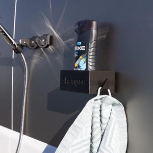 Könnte beinhalten: Ein schwarzes Shampoo-Regal mit dem Wort „Shampoo“ auf der Vorderseite, das eine Flasche Axe-Shampoo enthält. Ein weißes Handtuch hängt an einem Haken darunter. Links ist ein verchromter Duschkopf zu sehen.