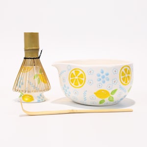 以下が含まれることがあります： セラミック製のミキシングボウル、竹製の泡立て器、竹製のスクープ。ボウルは白で、レモンと花の模様があります。泡立て器とスクープは天然の竹でできています。ボウルの直径は15cmです。