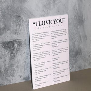 K&ouml;nnte beinhalten: Eine wei&szlig;e Karte mit rosa Herzen und schwarzem Text, der "I LOVE YOU" in Buchzitaten lautet. Die Karte enth&auml;lt Zitate &uuml;ber die Liebe aus verschiedenen B&uuml;chern und Autoren.