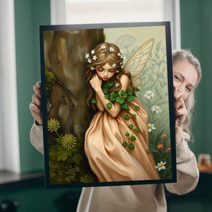 May include: A framed art print depicting a fairy with long brown hair, floral crown, and a flowing peach dress. The fairy has delicate wings and is surrounded by greenery and flowers. The artwork is set against a soft, natural background.