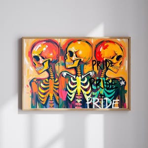 May include: A framed artwork featuring three stylized skeletons with vibrant orange and yellow skulls. The skeletons are painted with colorful rib cages and spines. The word "PRIDE" is written vertically in graffiti style. The artwork is set against a warm, orange background.
