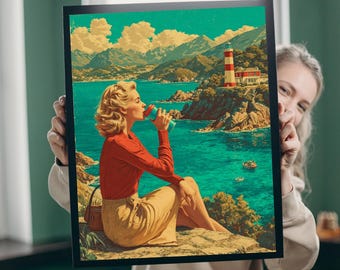 May include: A framed art print depicts a woman in a red top and yellow skirt drinking from a blue and red cup. The background features a coastal landscape with a lighthouse, mountains, and turquoise water. The art has a vintage, retro style.