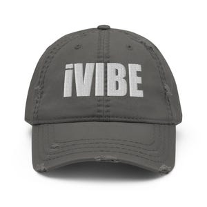 Peut inclure: Une casquette de baseball grise usée avec un texte brodé blanc qui dit "iVIBE".