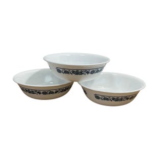 May include: Three white ceramic bowls with a blue floral design around the rim. The bowls are stacked in a triangular arrangement, showcasing their simple, elegant design. Ideal for serving soups, salads, or snacks.