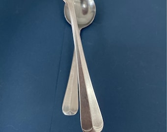 May include: Two silver utensils, a fork and a spoon, are crossed over each other. The utensils are on a blue background.