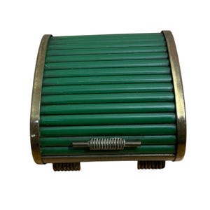May include: A rectangular box featuring a green roll-top lid constructed from horizontal slats. The frame is made of a metallic material with a brass-toned finish. A small, ribbed horizontal handle is centered on the front of the lid.