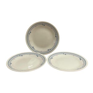 May include: Three white ceramic plates with a blue and red floral design. The plates include one round plate and two oval plates. The plates have a blue border with a floral pattern and red dots.