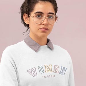 May include: A white sweatshirt with a rainbow coloured graphic that says "WOMEN IN STEM".