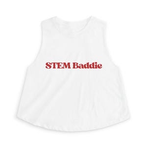 Könnte beinhalten: Weißes ärmelloses Crop-Top mit dem Text "STEM Baddie" in roten, fetten Buchstaben. Das Top hat einen runden Ausschnitt und einen leicht ausgestellten Saum. Der Stoff wirkt weich und leicht.