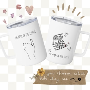 Peut inclure: Deux tasses de voyage blanches avec des couvercles argentés. L'une porte l'inscription "Engineer in the Streets" et une illustration de main. L'autre porte l'inscription "Freak in the Sheets" et une illustration d'ordinateur portable. Une bannière marron indique "you choose what side they see".