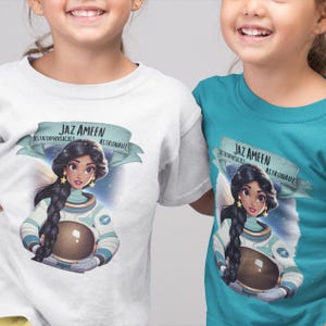 Könnte beinhalten: Zwei Kinder tragen weiße und türkisfarbene T-Shirts mit einem Motiv einer Comic-Prinzessin, die als Astronautin verkleidet ist. Der Text auf den Shirts lautet "Jaz Ameen Astrophysicist Astronaut".