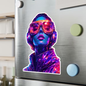May include: A vibrant sticker featuring a futuristic portrait of a person with neon blue skin, wearing large pink goggles and headphones. The jacket is a shiny, iridescent purple. The artwork has a sci-fi or cyberpunk theme.