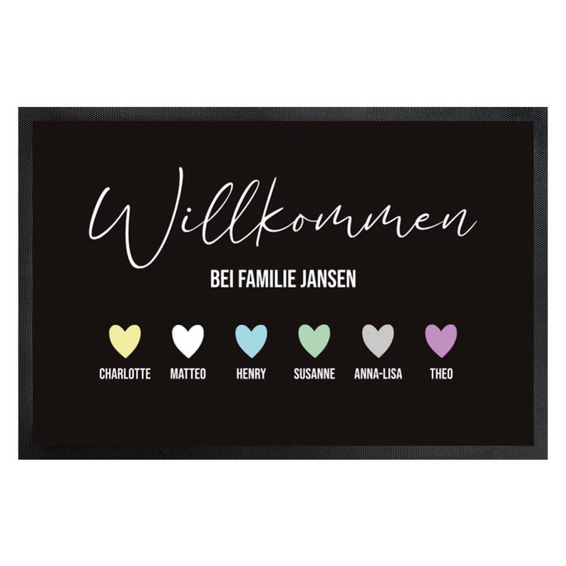 May include: Black doormat with white script reading "Willkommen" above "Bei Familie Jansen." Below are six colorful hearts with names: Charlotte, Matteo, Henry, Susanne, Anna-Lisa, and Theo. The mat has a black border.