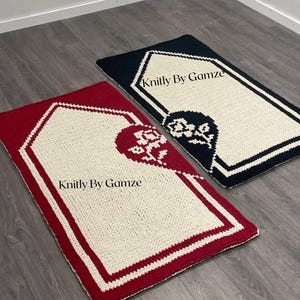 Puede incluir: Dos alfombras de oración rectangulares tejidas. Una es roja con un centro blanco y un diseño floral. La otra es azul marino con un centro blanco. Ambas tienen un borde blanco y el texto "Knittly By Gamze".