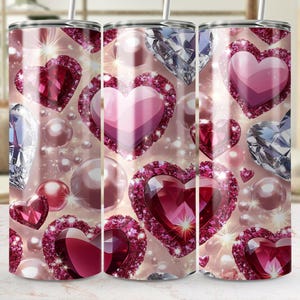 May include: Three stainless steel tumblers with a pink, white, and red heart design. The hearts are surrounded by sparkling diamonds and pearls.