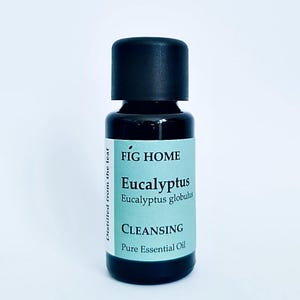Könnte beinhalten: Eine kleine, dunkelbraune Glasflasche mit schwarzem Verschluss. Das Etikett ist hellblau und trägt die Aufschrift "FIG HOME Eucalyptus Eucalyptus globulus CLEANSING Pure Essential Oil".