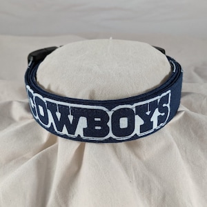 May include: A navy blue belt with white lettering that reads "COWBOYS".