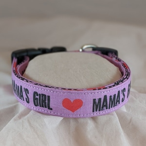 May include: Purple dog collar with black text that reads "Mama's Girl" with a red heart in between the words.