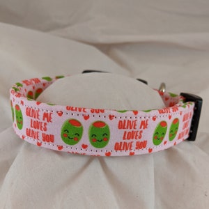 May include: Pink dog collar with a repeating pattern of green olives with red faces and the text "Olive me loves olive you".