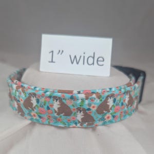 May include: A 1-inch wide dog collar with a blue background and a pattern of brown dogs and pink flowers.