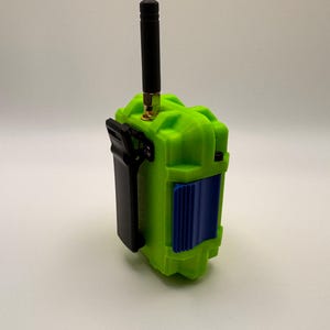 May include: A lime green electronic device with a black antenna and a black clip. The device has a blue panel on the front. The antenna is approximately 4 inches long.
