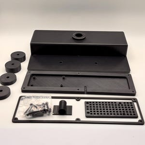 May include: Black rectangular box with a circular opening, disassembled with a rectangular frame, a grid, and several round components. Also included are screws and other small parts in a clear plastic bag.