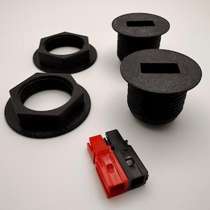 May include: Two black plastic electrical outlet covers with a rectangular opening and two black plastic mounting rings. A red and black electrical connector is also included.
