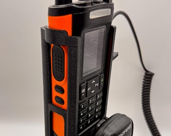 May include: Black and orange Baofeng two-way radio with a black microphone. The radio has a screen, a keypad, and an antenna. The radio is in a black holder. The microphone is connected to the radio with a black cord.