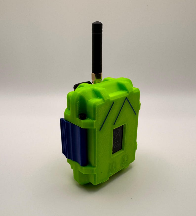 May include: A neon green electronic device with a black antenna and a blue component. The device has a small digital display and is set against a white background. The device has a rugged, industrial design.